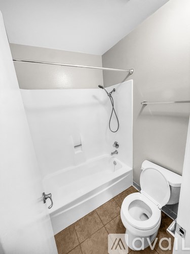 A small bathroom with a toilet, tub and shower.