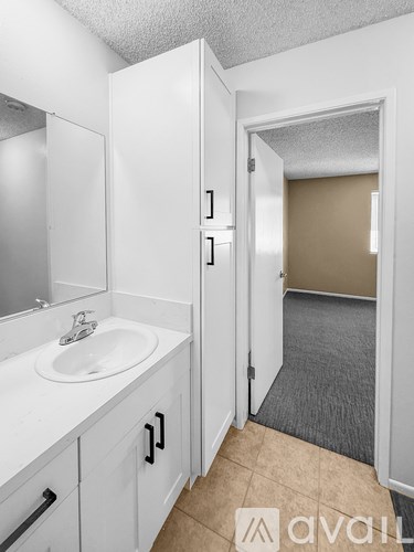A bathroom with a sink, mirror, and cabinets.