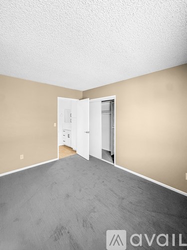 A room with a white ceiling, tan walls, and a grey floor with a white door.