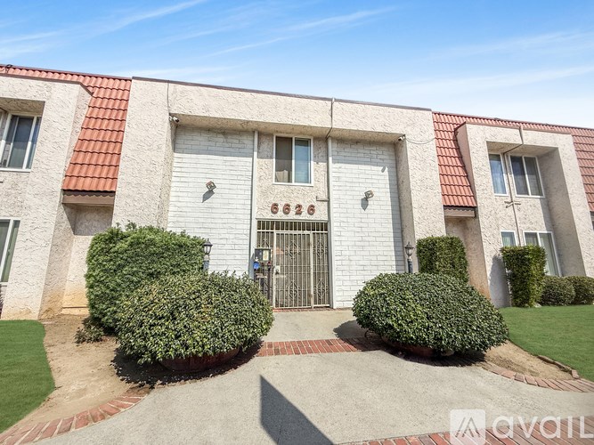 A white building with a red tile roof and a black gate in the center.