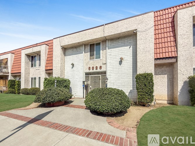 A building with a red roof and white walls has a gate in the center.