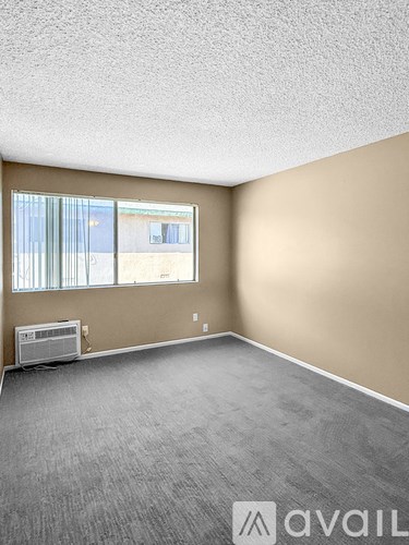 A room with a carpeted floor and a window with blinds.