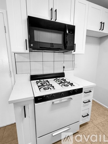 A black microwave oven is mounted above a white stove in a kitchen.