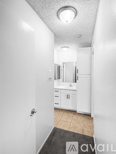 A white bathroom with a sink, mirror, and cabinets.