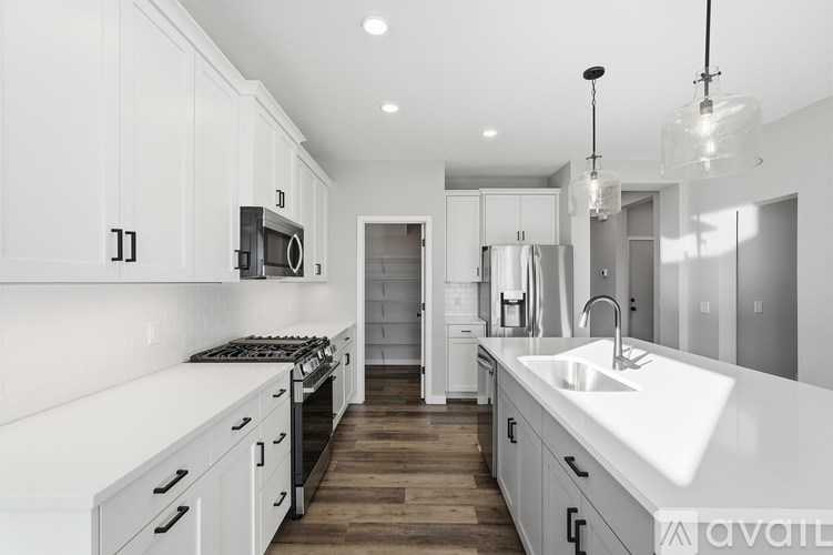 A modern kitchen with white cabinets and a wooden floor.
