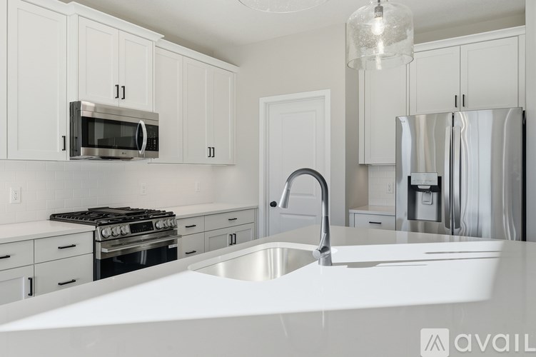 A modern kitchen with white cabinets and stainless steel appliances.