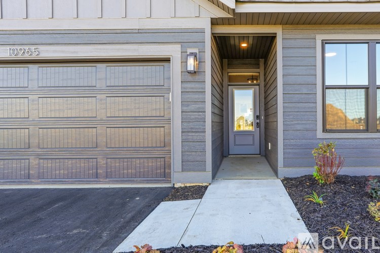 A grey house with a white door and a garage door.