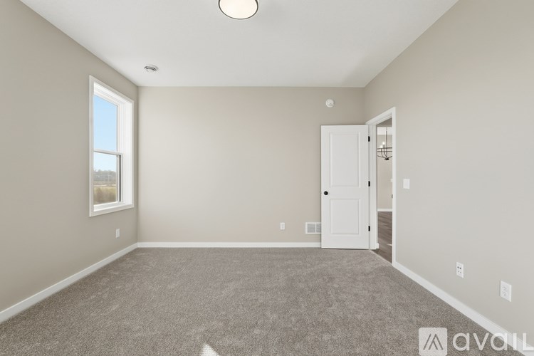 A room with a carpeted floor, a door, and a window.