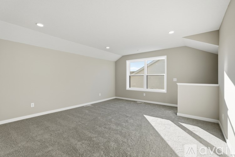 A spacious room with a window and carpeted floor.