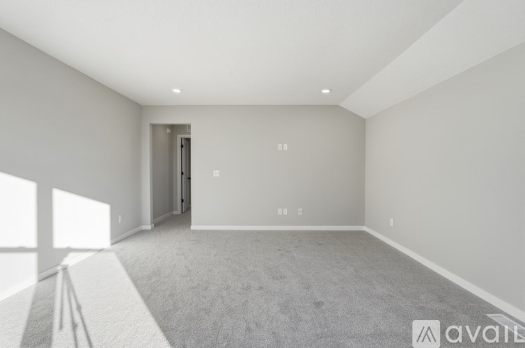A spacious room with a carpeted floor and a doorway leading to another room.
