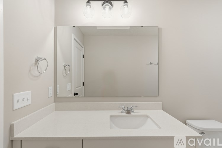 A white bathroom with a sink, mirror, and toilet.