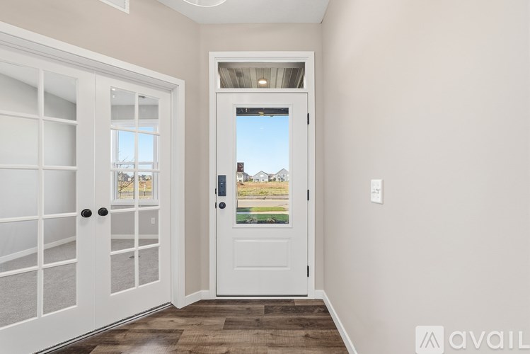 A white door with a glass window is in a room with a wooden floor.