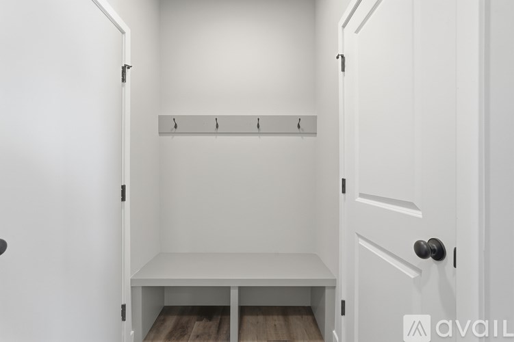 A white closet with a bench and coat hooks.