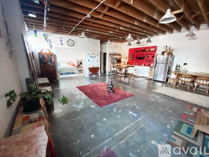 A room with a wooden ceiling and a red rug in the middle.