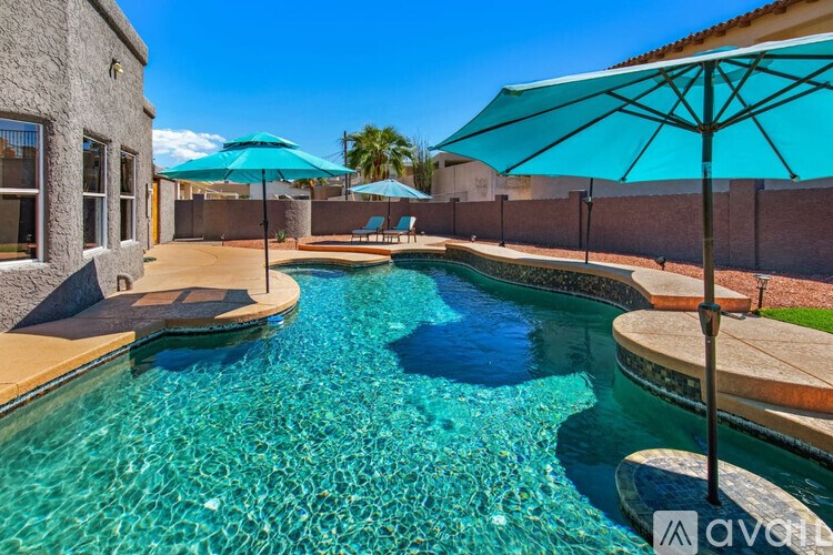 A swimming pool with a blue umbrella and a wall on the left side.