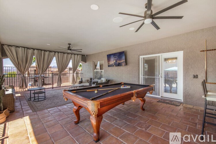 A pool table is in the middle of a patio with a ceiling fan.