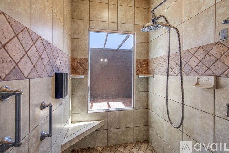 A tiled bathroom with a window and a shower.