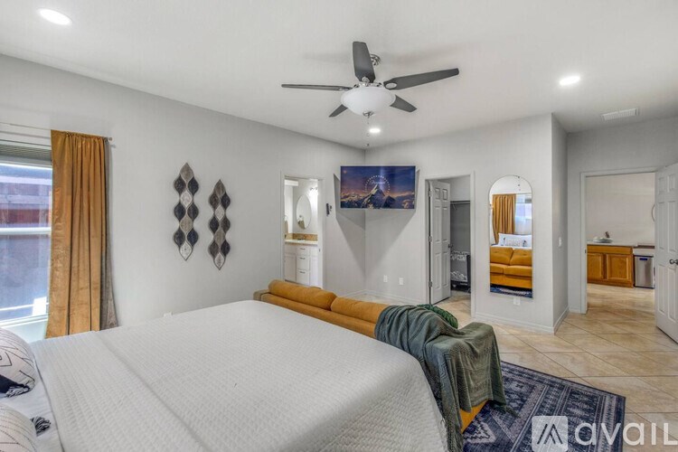 A bedroom with a large bed and a ceiling fan.