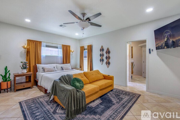 A bedroom with a bed, a couch, and a ceiling fan.