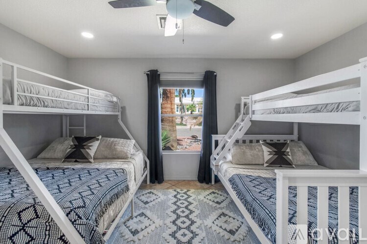 A room with two bunk beds and a ceiling fan.