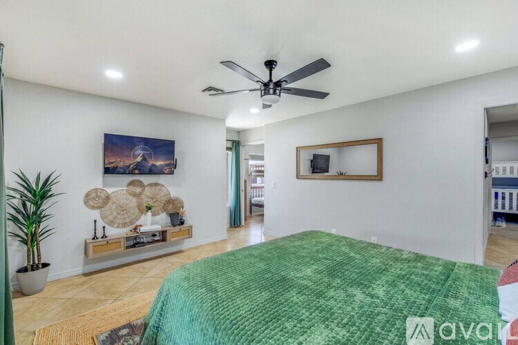 A bedroom with a green bedspread and a ceiling fan.