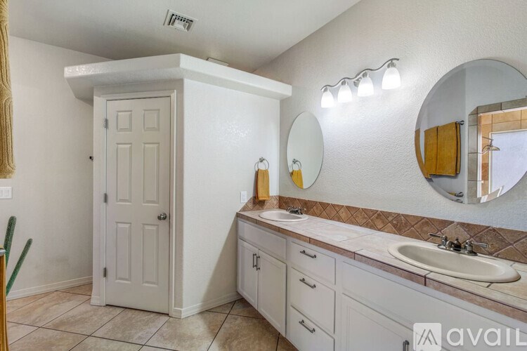 A bathroom with a white door, a round mirror, and a sink.