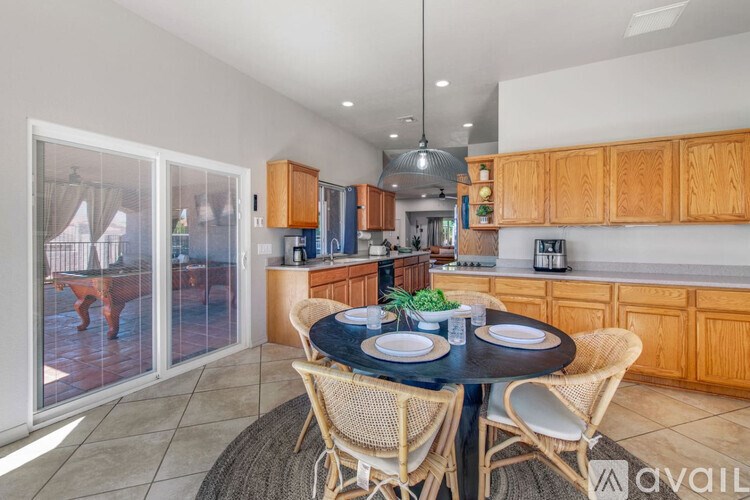 A dining room with a table set for two and chairs around it.