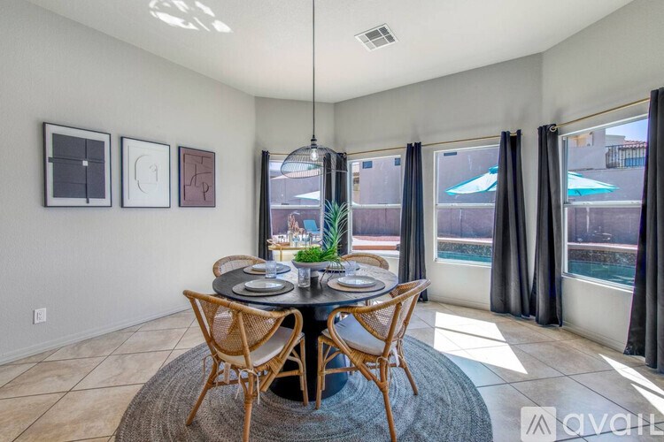 A dining room with a table set for two and a view of a pool through the window.