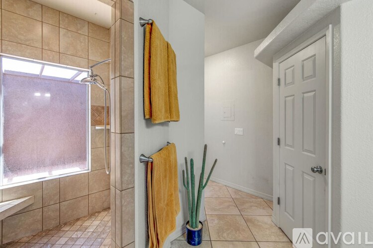A bathroom with a tiled shower and a yellow towel hanging on the wall.
