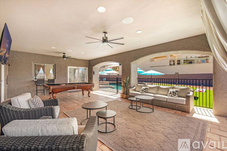 A patio with a couch, chairs, and a table with a glass top.