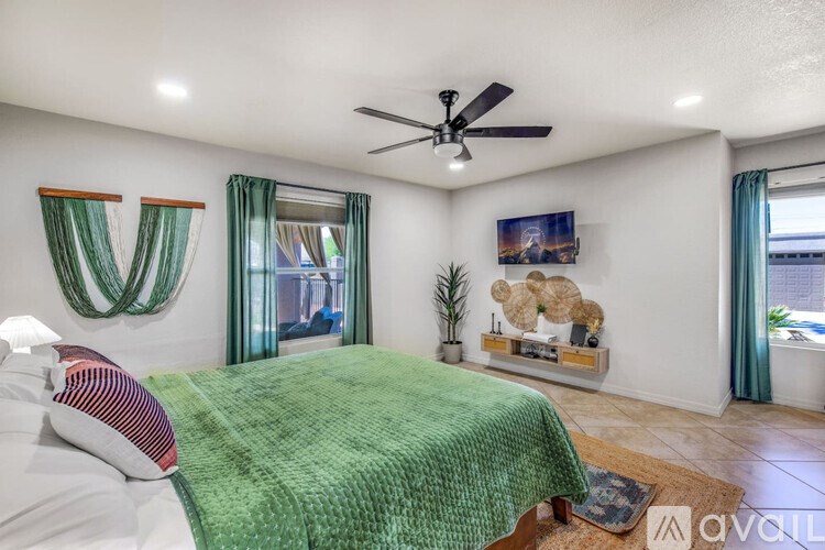 A bedroom with a bed, a ceiling fan, and a window with curtains.