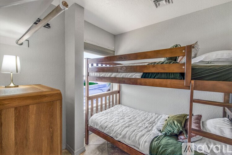 A bedroom with a bunk bed and a wooden nightstand.