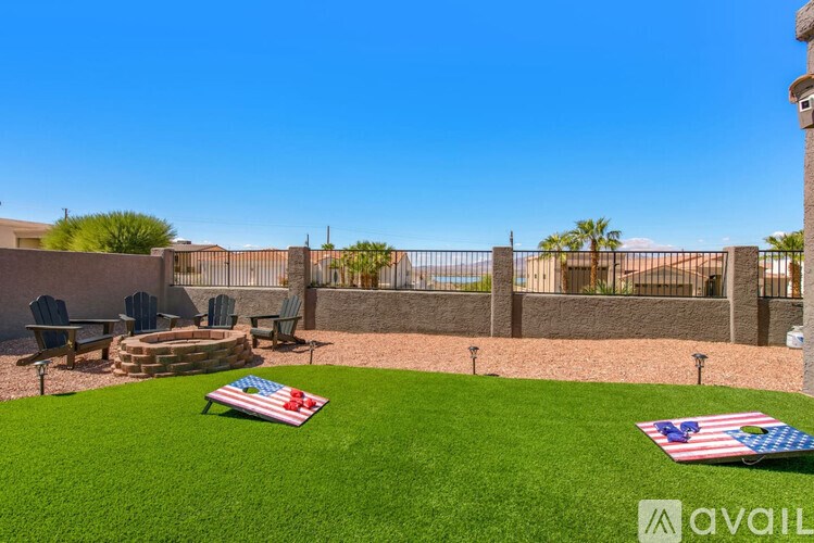 A backyard with a fence, a fire pit, and two American flags on the grass.