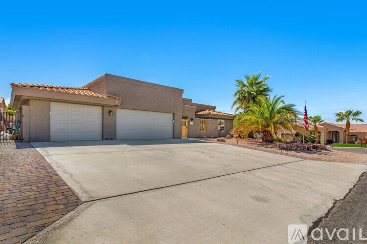 A house with a driveway and palm trees in front.