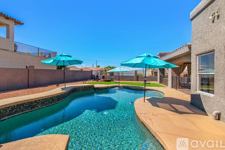 A pool with a blue umbrella and a brownish poolside.