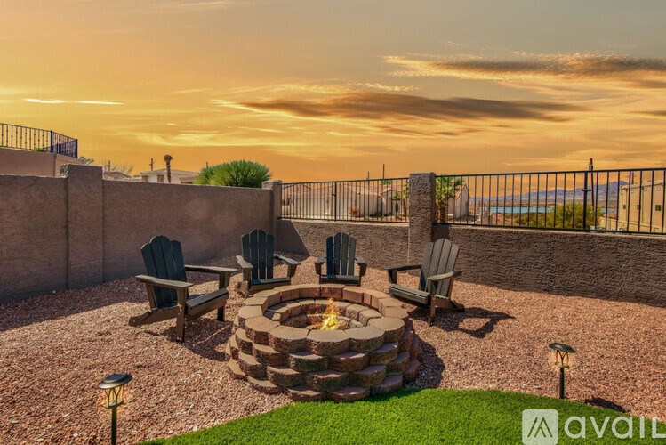 A backyard with a fire pit and chairs.