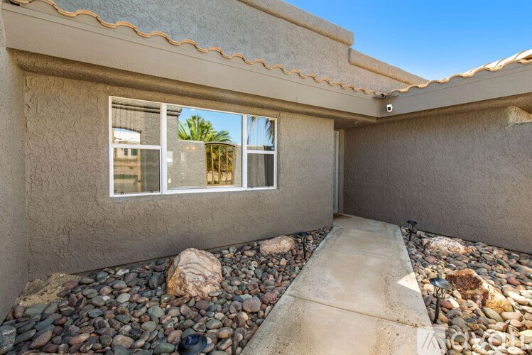 A house with a window and a gravel path leading to it.