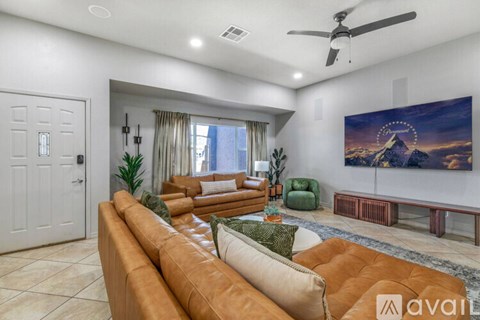 A living room with a brown leather couch and a painting on the wall.