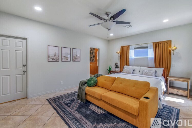 A living room with a yellow couch and a bed with white pillows.