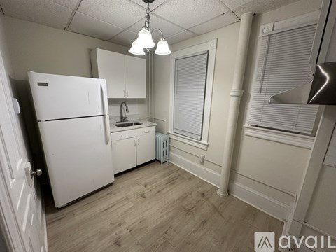 A kitchen with a white fridge and wooden floors.