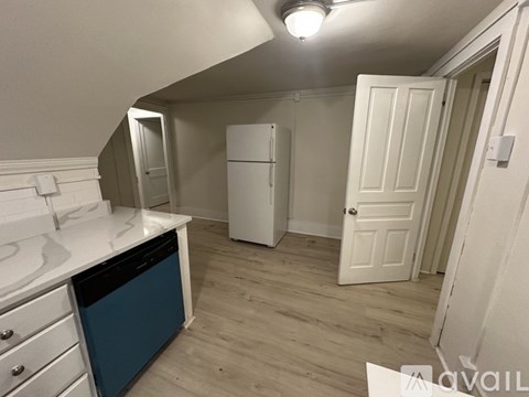A kitchen with a white counter top and a blue bin.