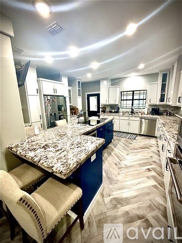 A kitchen with a granite countertop and a blue accent wall.