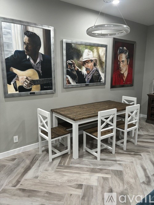 A dining room with a wooden table and chairs and three framed pictures on the wall.
