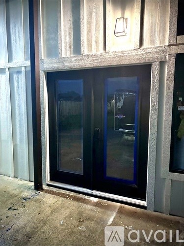 A glass door with a black frame is installed in a white wall.