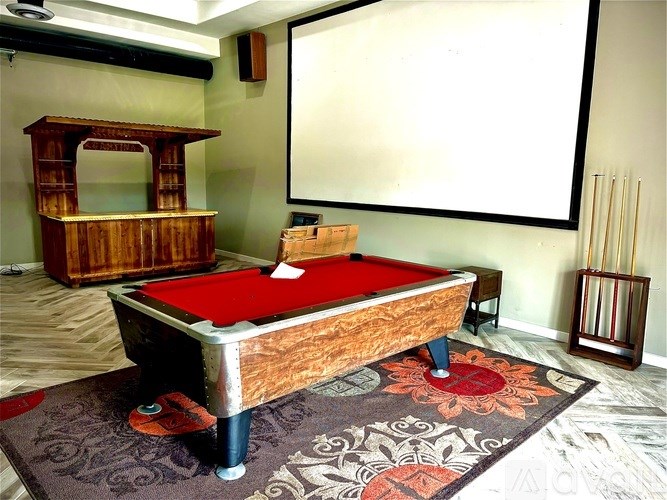 A pool table with a red cloth and a wooden cabinet in the background.