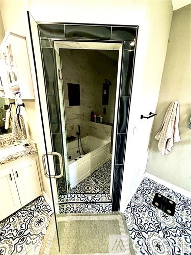 A bathroom with a glass shower door and a black and white floor.
