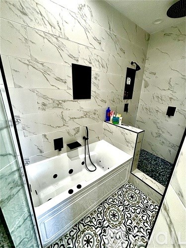 A white marble bathroom with a black shower head.