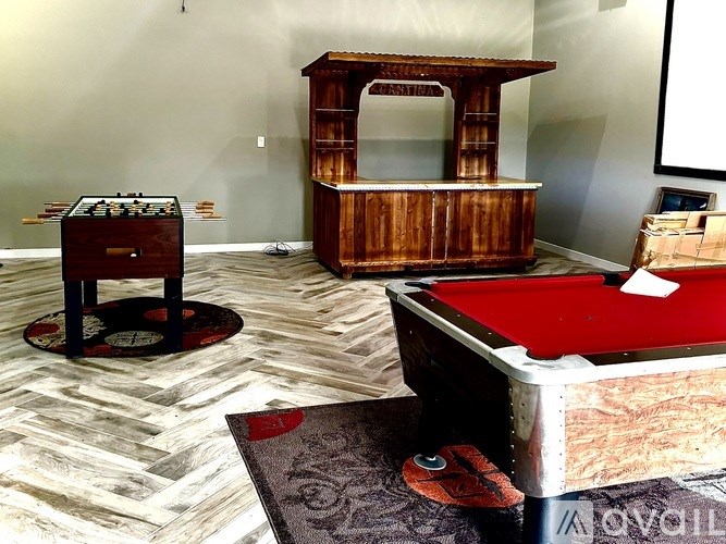 A room with a pool table, air hockey table, and a foosball table.