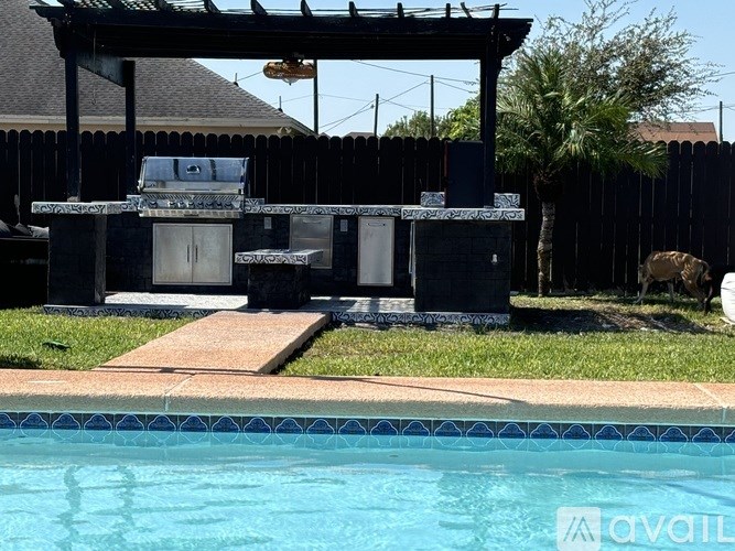 A pool with a barbecue grill and a table in the backyard.