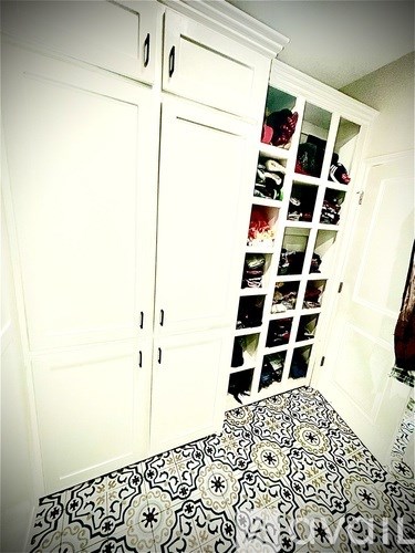 A hallway with a black and white tiled floor and a white cabinet with drawers and shelves.